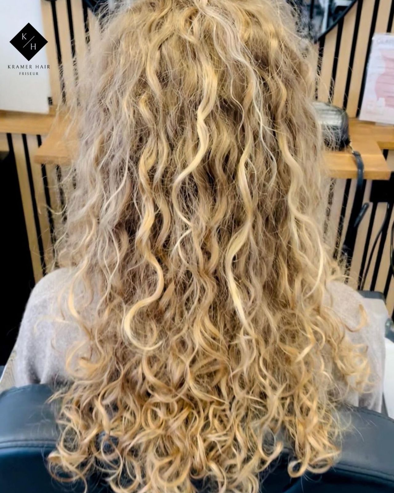 Kundin hat eine natürlich aussehende Dauerwelle in langelm Haar bekommen 