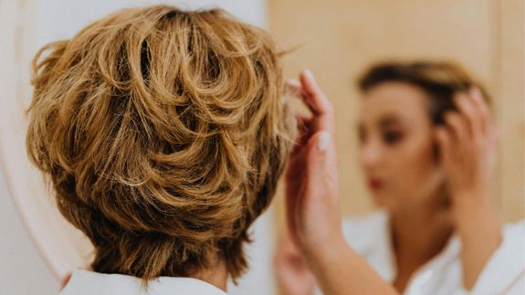 Frau frisiert sich im Spiegel